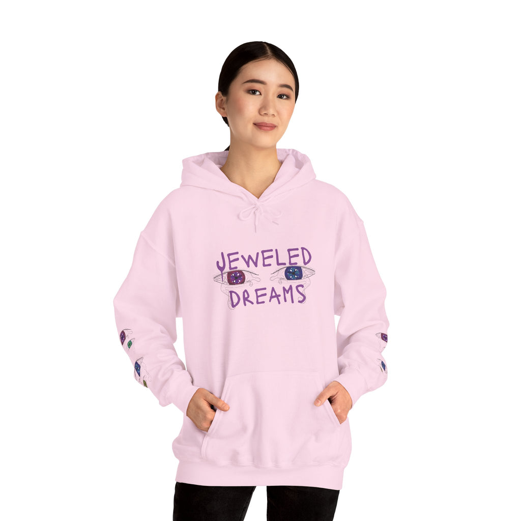 Person wearing a pink hoodie with 'Jeweled Dreams' text on a pink background
