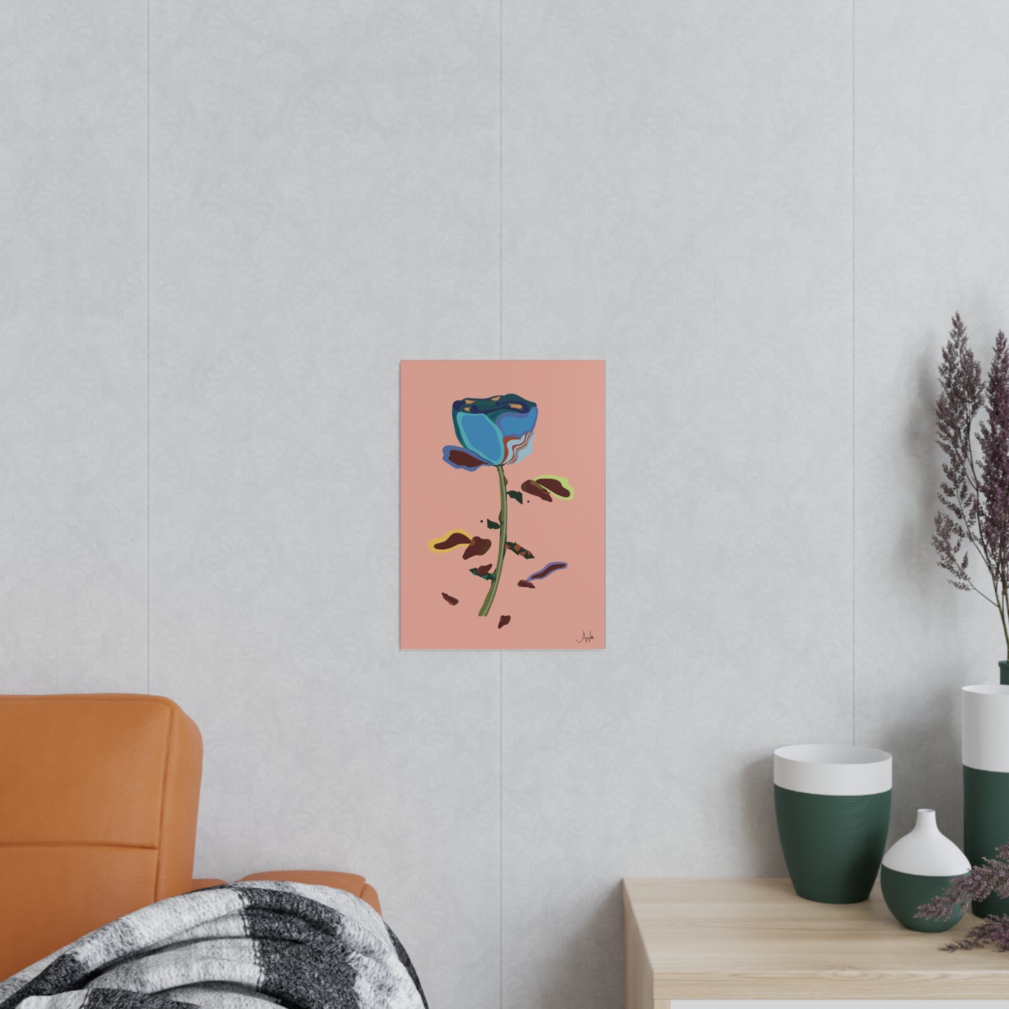 Art print of a blue flower on a pink background hanging on a light gray wall above an orange chair.