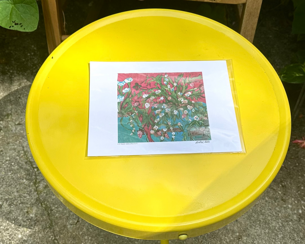 A square art print featuring a colorful floral  strawberry plant design, displayed on a round yellow table outdoors.