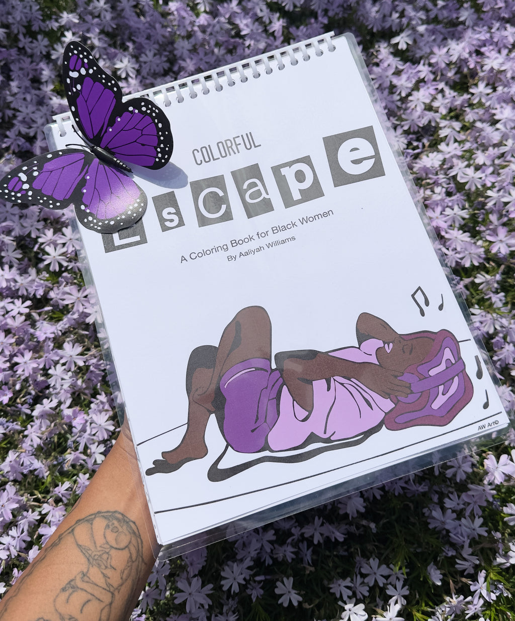 Purple flower background with a coloring book called "Colorful Escape, A  Coloring Book for Black Women." A girl listening to her music with headphones on with monochromatic purples. A purple and black butterfly in the upper left corner of the photo. 
