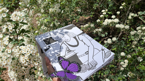 Notebook with a butterfly illustration held in front of white flowers